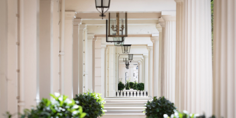 View down a serene corridor with classic white columns and ornate hanging lanterns